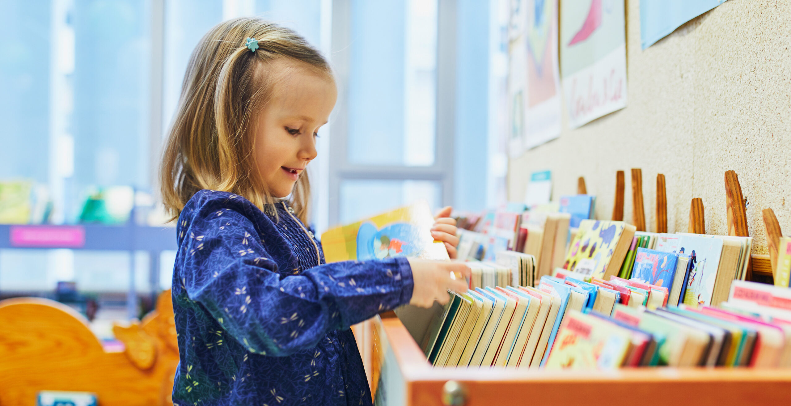 Little girl looking through books in a library